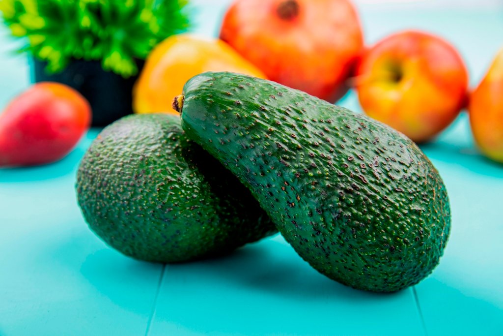 side view of green and fresh avocado on blue background